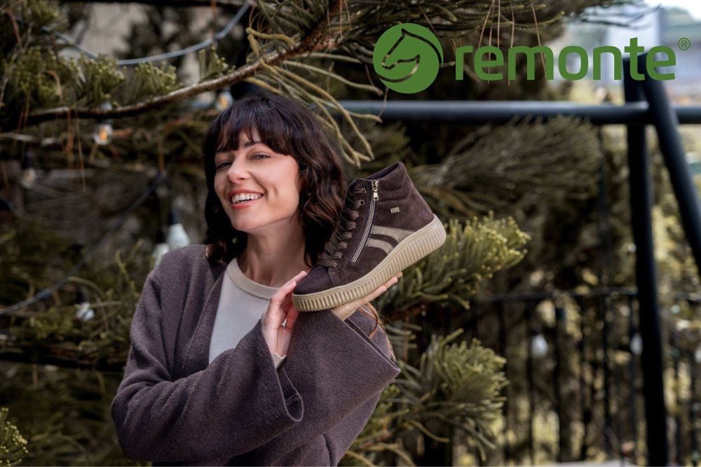 A woman outdoors holds up a brown high-top sneaker with a beige sole. The image has a green 'remonte' logo overlay in the top right corner.